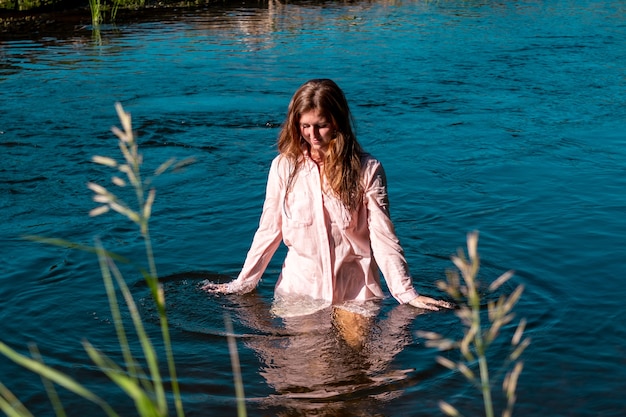 Felice giovane donna si bagna nel fiume godendosi l'acqua fresca