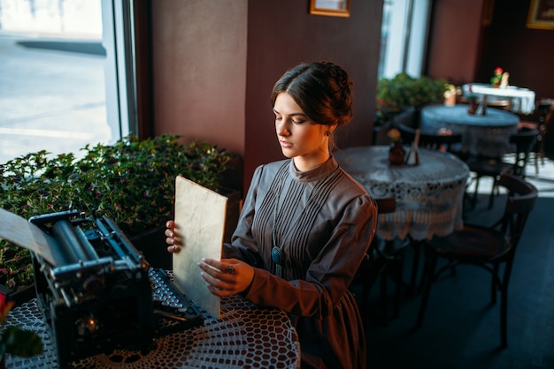 Felice giovane donna si siede al tavolo nella caffetteria