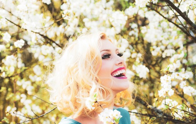 Felice giovane donna sorridente con fiori di primavera in giardino foto di moda all'aperto di bella giovane donna