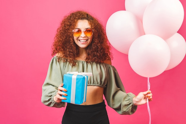 Felice giovane donna sorridente riccia con palloncini