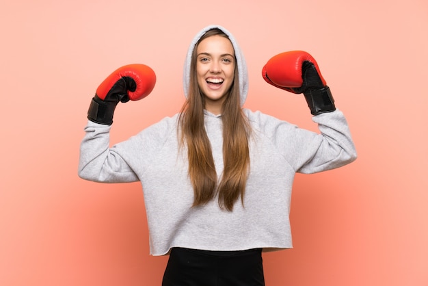 Felice giovane donna sportiva rosa con guantoni da boxe