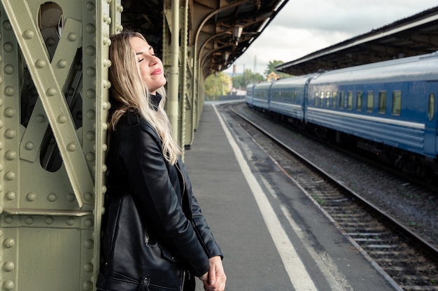 Felice giovane donna sul binario della stazione ferroviaria