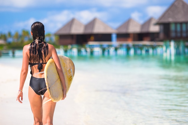 Felice giovane donna surf in spiaggia con una tavola da surf