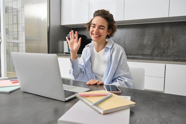 Felice giovane donna tutor insegnante studenti online ragazza si collega a una riunione di lavoro remota da casa sua