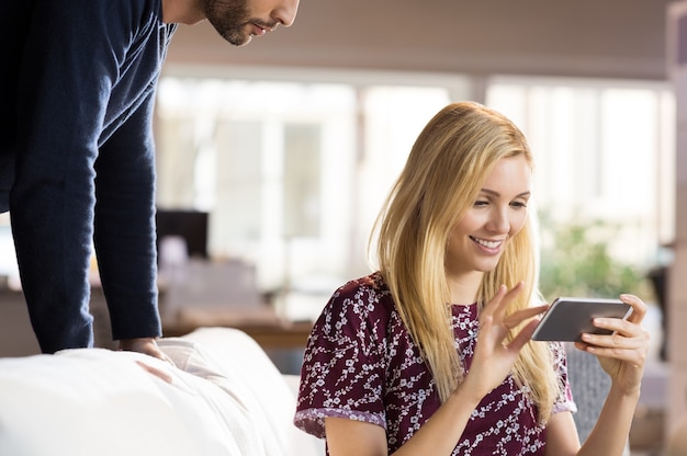 Felice giovane donna utilizza lo smartphone mentre l'uomo la guarda.