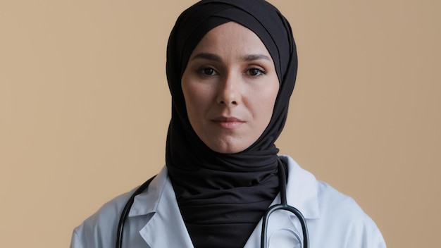 felice giovane dottoressa musulmana medico in hijab indossa camice medico bianco che guarda l'obbiettivo