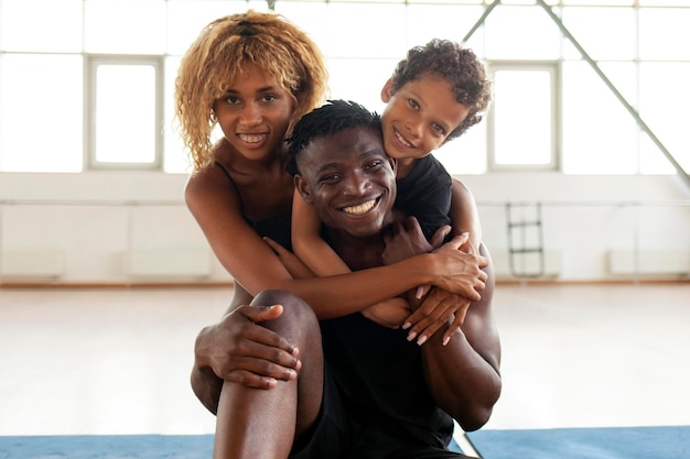 felice giovane famiglia afroamericana che abbraccia e sorride in palestra mamma papà e figlio amano insieme