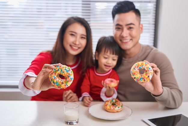 Felice giovane famiglia con bambini che si godono la colazione in una sala da pranzo bianca e soleggiata con una grande finestra con vista sul giardino