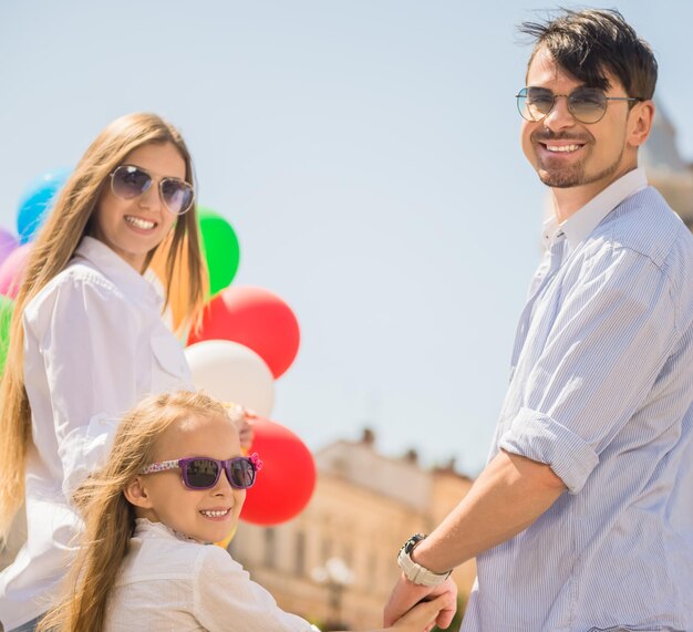 Felice giovane famiglia con un mazzo di palloncini che si divertono all'aperto in una giornata di sole.