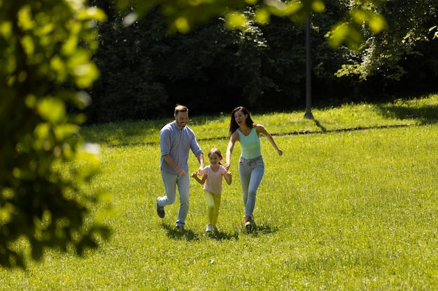 Felice giovane famiglia con una piccola figlia carina che corre nel parco in una giornata di sole