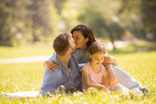 Felice giovane famiglia con una piccola figlia carina che si diverte nel parco in una giornata di sole