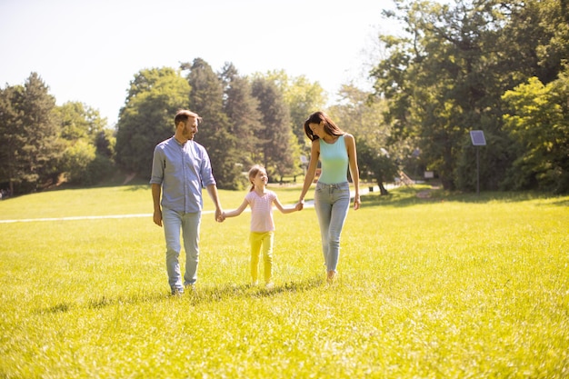 Felice giovane famiglia con una piccola figlia carina che si diverte nel parco in una giornata di sole