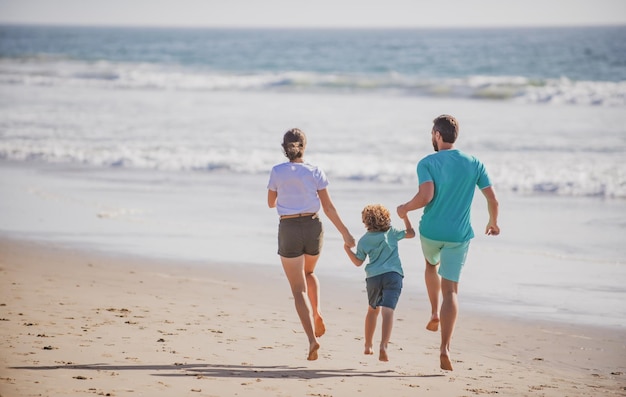 Felice giovane famiglia correre e saltare sulla spiaggia estiva attività per il tempo libero in famiglia concetto bambino con i genitori