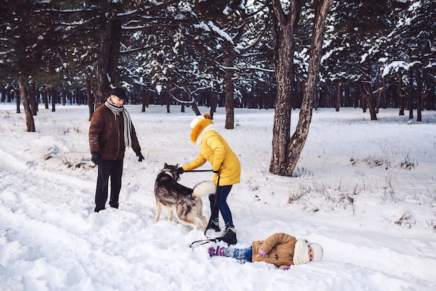 Felice giovane famiglia divertendosi a giocare con il cane a winter park