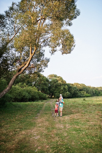 Felice giovane famiglia: madre, padre, figlio di due bambini sulla natura divertendosi.