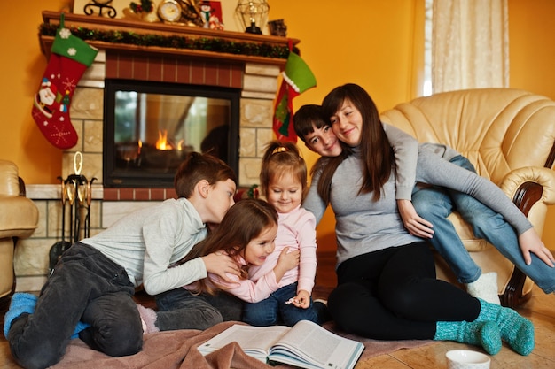 Felice giovane famiglia numerosa a casa da un camino nel caldo soggiorno in una giornata invernale