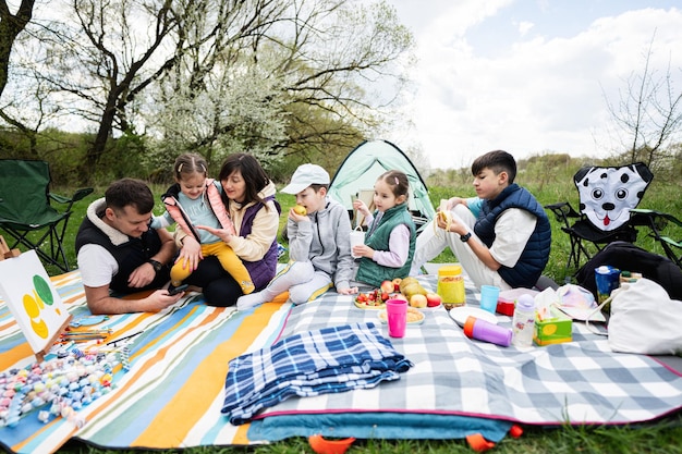 Felice giovane famiglia numerosa con quattro bambini che si divertono e si divertono all'aperto durante il picnic