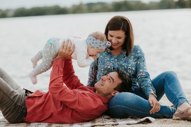 Felice giovane famiglia seduta vicino all'acqua