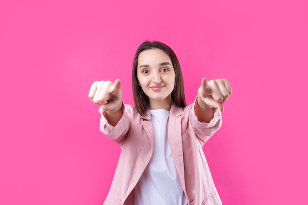 Felice giovane femmina caucasica in una giacca rosa che punta le dita lontano