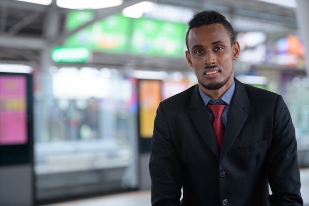 Felice giovane imprenditore africano in attesa presso la stazione ferroviaria