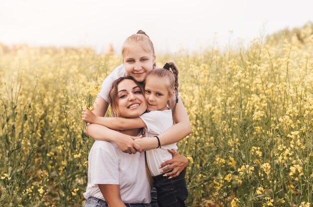 Felice giovane madre coccola con le sue figlie in estate sul campo dello stupro. Felicità con la famiglia