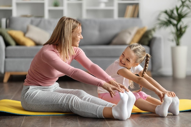 Felice giovane madre e figlia che fanno sport insieme a casa