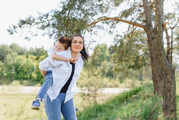 Felice giovane madre sta giocando con il suo bambino in un parco su un prato verde