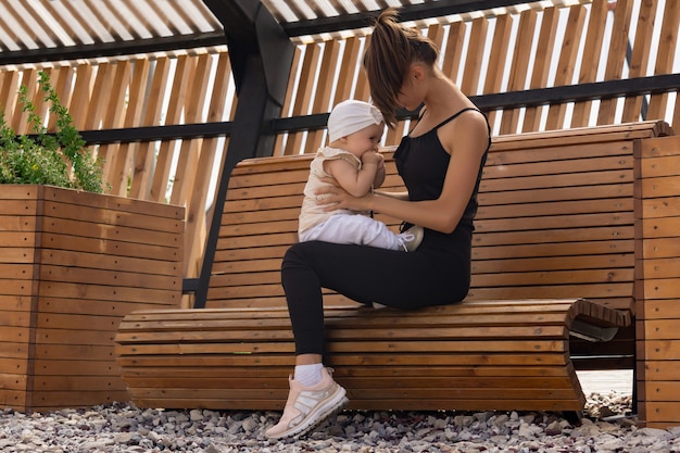 Felice giovane mamma con la sua bambina che gioca su una panchina del parco