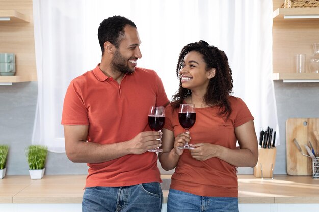 Felice giovane marito e moglie neri con le stesse magliette con bicchieri di vino si godono il tempo libero insieme