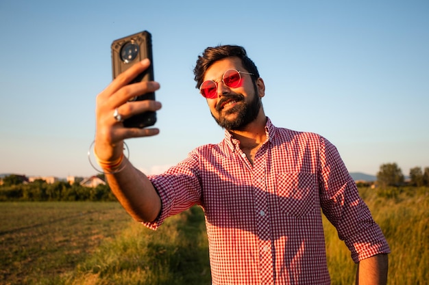 Felice giovane prendendo selfie nel campo estivo