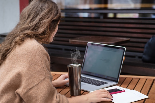 Felice giovane ragazza che lavora in una caffetteria con un computer portatile