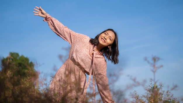 Felice giovane ragazza in piedi con il cielo blu