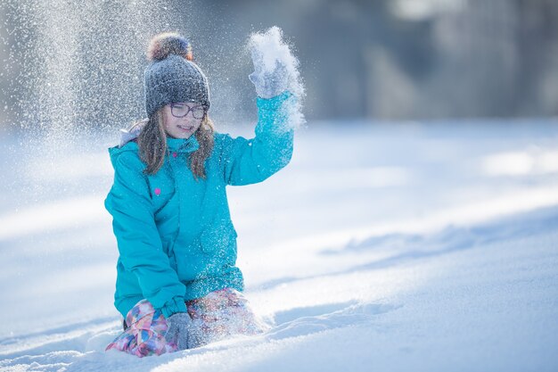 Felice giovane ragazza Pre-Teen in abiti caldi, giocando con la neve.