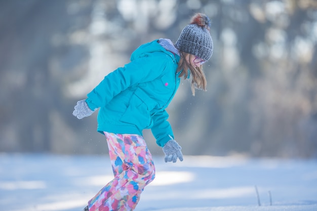 Felice giovane ragazza Pre-Teen in abiti caldi, giocando con la neve.