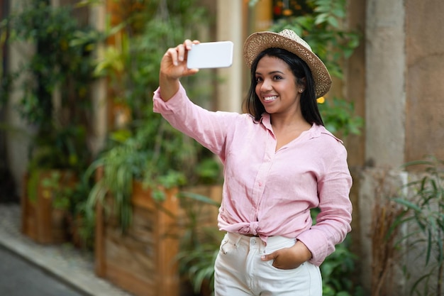 Felice giovane signora nera in casual prendendo selfie al telefono goditi il viaggio nella nuova città girando video per i social network