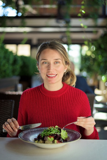 Felice giovane sorridente e mangiare insalata