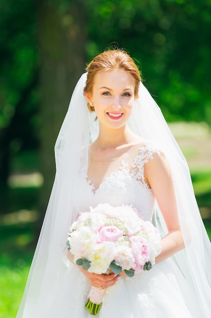 Felice giovane sposa in un delicato abito da sposa bianco e velo dentro