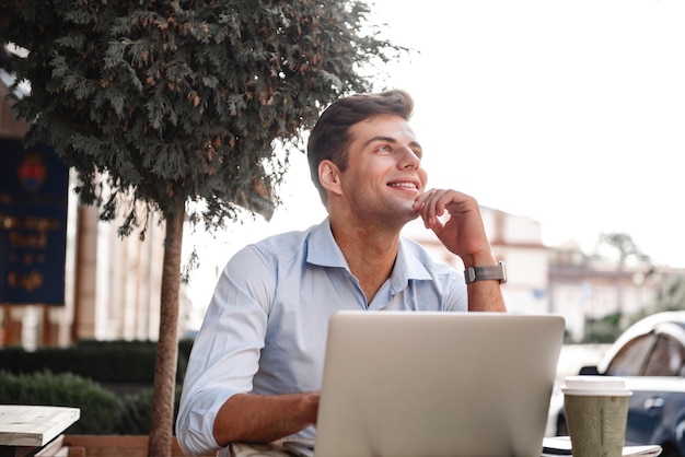 Felice giovane uomo alla moda che lavora al computer portatile