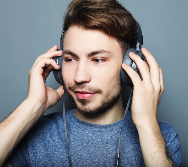 Felice giovane uomo alla moda che regola il suo annuncio cuffie sorridente wh