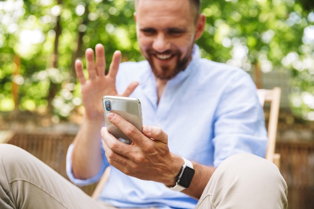 Felice giovane uomo barbuto all'aperto parlando dal telefono cellulare.