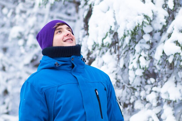 Felice giovane uomo bello in vestiti caldi e cappello godendo una buona giornata