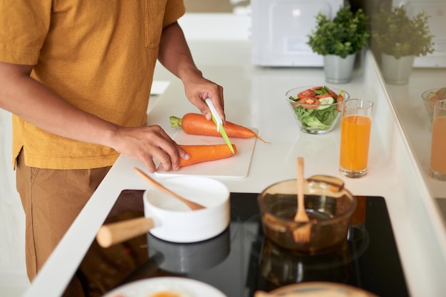 Felice giovane uomo che taglia le verdure in cucina