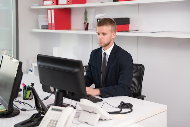 Felice giovane uomo d'affari lavorare in ufficio moderno sul computer