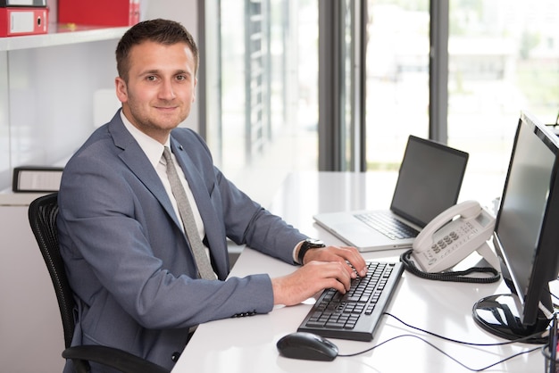 Felice giovane uomo d'affari lavorare in ufficio moderno sul computer