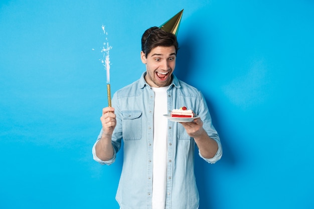 Felice giovane uomo festeggia il compleanno in cappello del partito