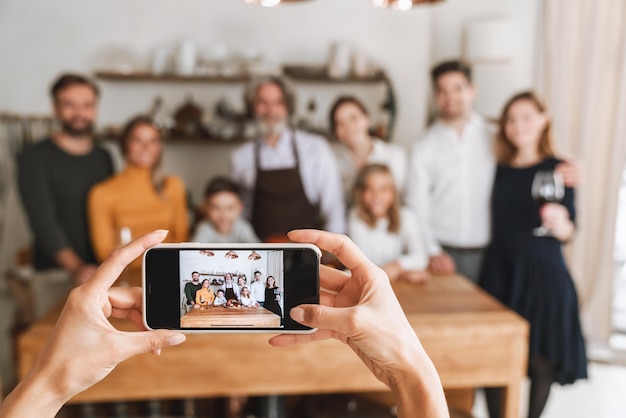 Felice grande famiglia in posa per la macchina fotografica mentre si sta in piedi al tavolo della cucina e festeggia la vigilia di Natale