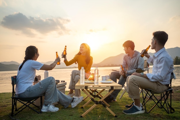 Felice gruppo di amici asiatici Suona la chitarra e canta godendoti il campeggio e bevendo birra