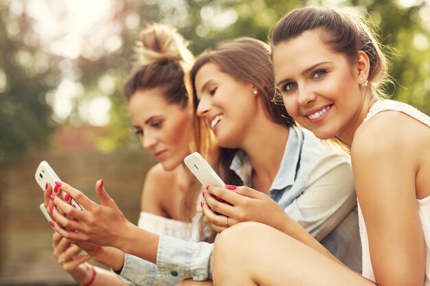 felice gruppo di amici con smartphone seduti all'aperto