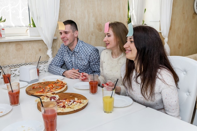 Felice gruppo di amici nella caffetteria che mangia pizza