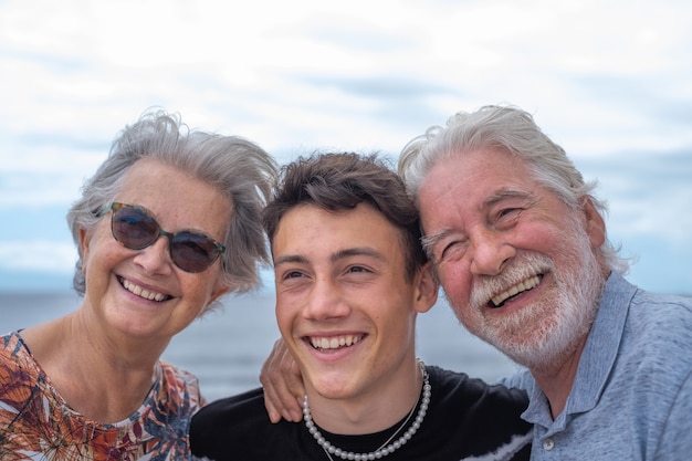 Felice gruppo di nonni con nipote adolescente seduto all'aperto in mare, abbracci e sorrisi. Belle persone che si divertono insieme